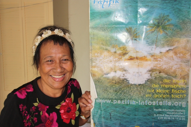 Lijon Eknilang vor einem Plakat des Pazifik-Netzwerkes